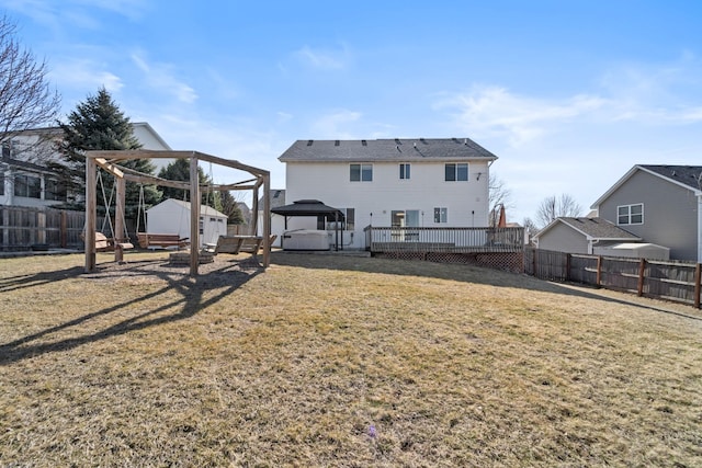 back of house with a deck, a fenced backyard, a shed, a yard, and an outdoor structure