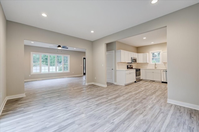 unfurnished living room with ceiling fan, light hardwood / wood-style flooring, and sink