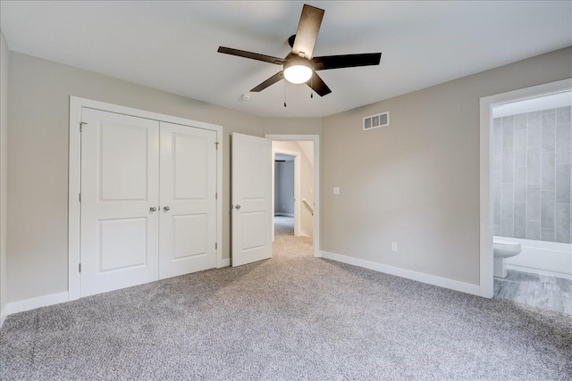 unfurnished bedroom featuring ceiling fan, a closet, ensuite bathroom, and light carpet