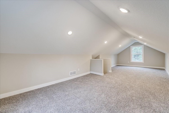 additional living space with carpet, a textured ceiling, and vaulted ceiling