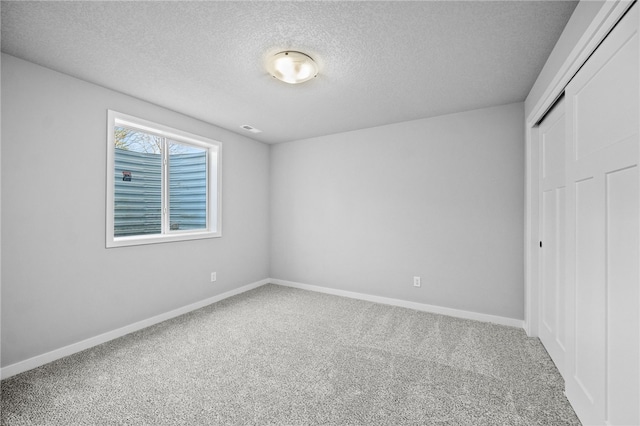 unfurnished bedroom with a textured ceiling, carpet floors, and a closet