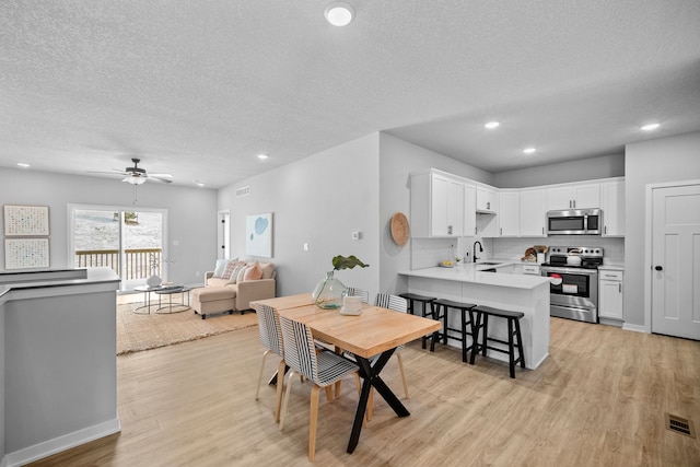 dining room featuring a textured ceiling, light hardwood / wood-style floors, ceiling fan, and sink