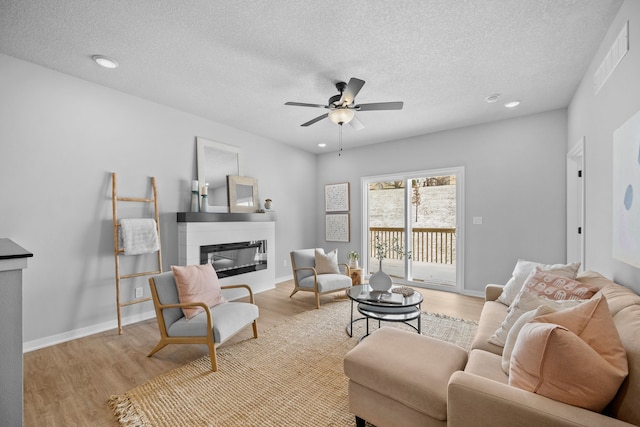 living room featuring a textured ceiling, light hardwood / wood-style flooring, and ceiling fan