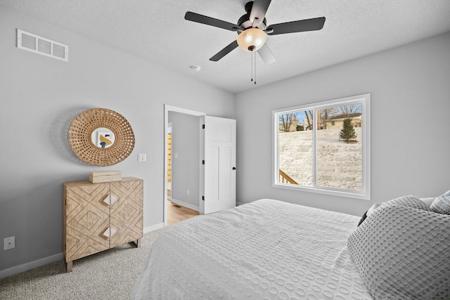 bedroom featuring ceiling fan, light colored carpet, and a textured ceiling