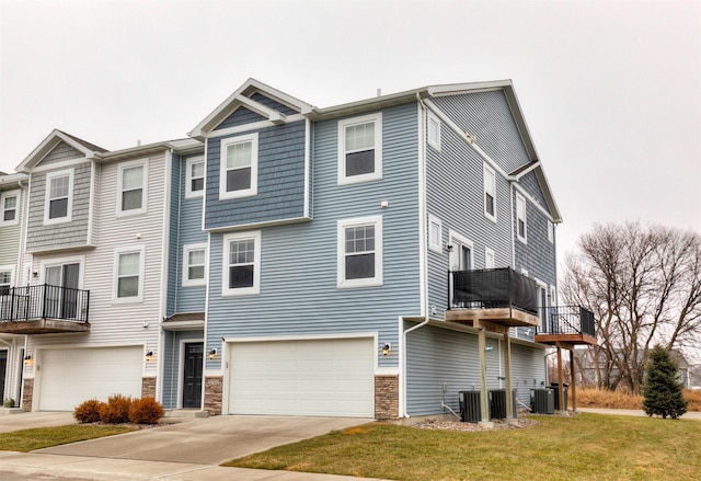 view of property with a front lawn, a garage, and central AC unit