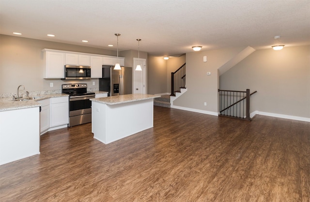 kitchen with light stone counters, stainless steel appliances, sink, decorative light fixtures, and white cabinets