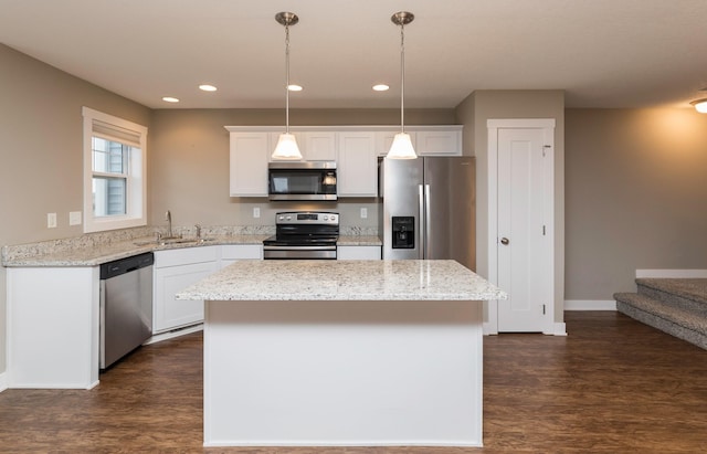 kitchen with stainless steel appliances, sink, decorative light fixtures, a center island, and white cabinetry