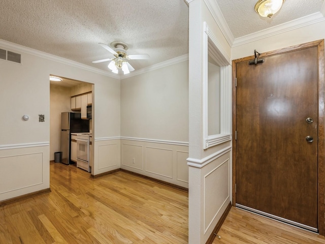 entryway with light wood-type flooring, a textured ceiling, ceiling fan, and crown molding