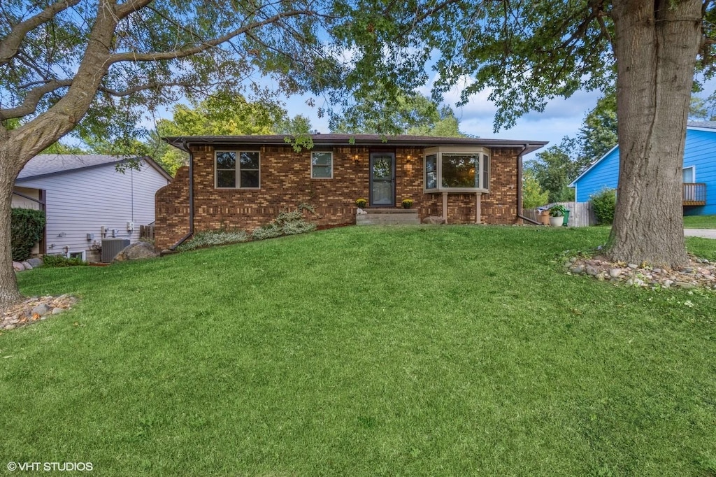 ranch-style home featuring central AC unit and a front lawn