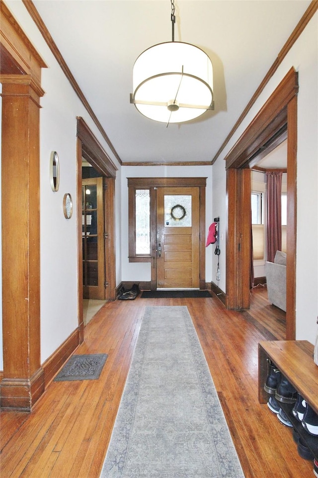 foyer entrance with wood-type flooring, baseboards, and ornamental molding