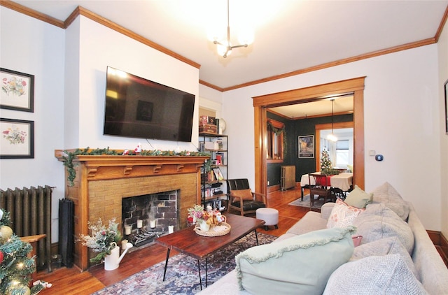 living room featuring a chandelier, radiator heating unit, a fireplace, and crown molding