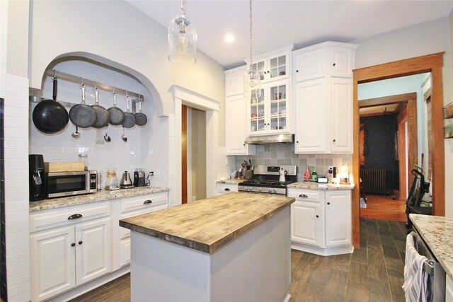 kitchen featuring white cabinets, decorative backsplash, a kitchen island, butcher block counters, and stainless steel appliances