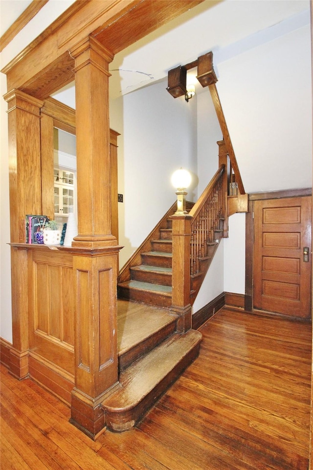 staircase with decorative columns and hardwood / wood-style flooring