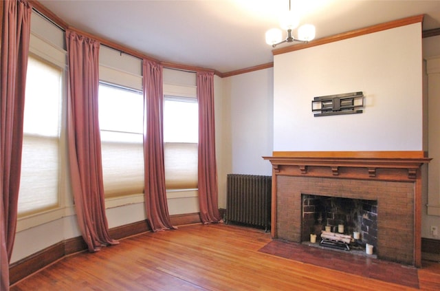 unfurnished living room featuring ornamental molding, wood finished floors, radiator, a fireplace, and baseboards