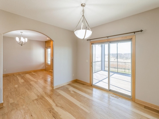 spare room with light hardwood / wood-style floors and a chandelier