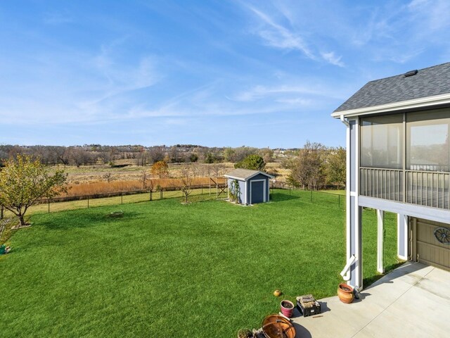 view of yard featuring a rural view, a patio area, and a storage shed