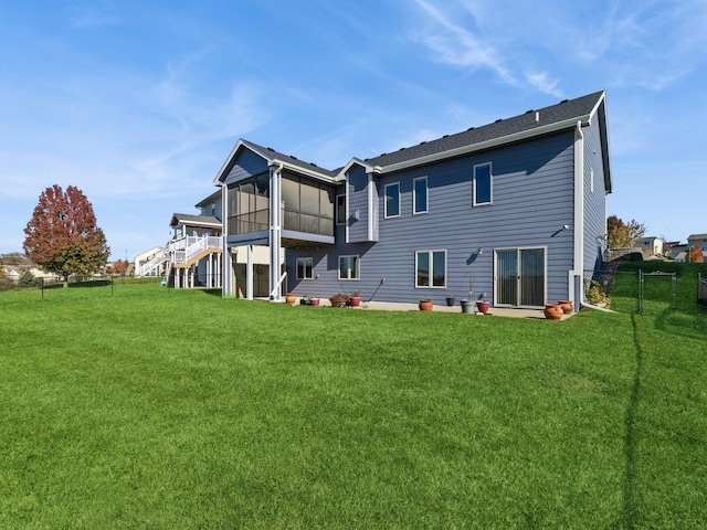 rear view of house with a sunroom and a lawn