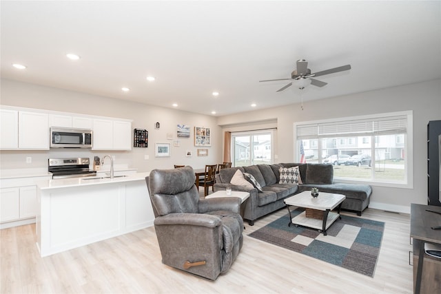 living room featuring plenty of natural light, ceiling fan, light wood-type flooring, and sink