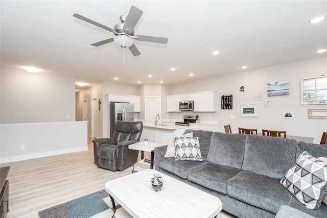 living room with ceiling fan, light wood-type flooring, and sink