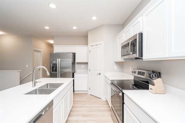 kitchen featuring white cabinets, sink, light wood-type flooring, and stainless steel appliances