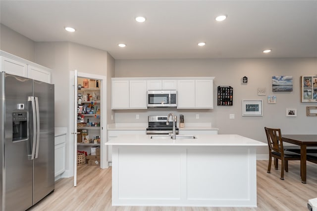 kitchen featuring white cabinets, sink, an island with sink, and stainless steel appliances