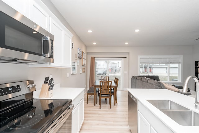 kitchen with light wood-type flooring, white cabinetry, sink, and appliances with stainless steel finishes