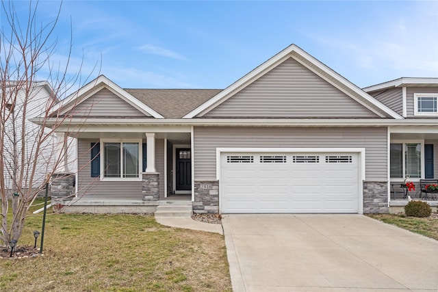 view of front of home featuring covered porch, a garage, and a front lawn