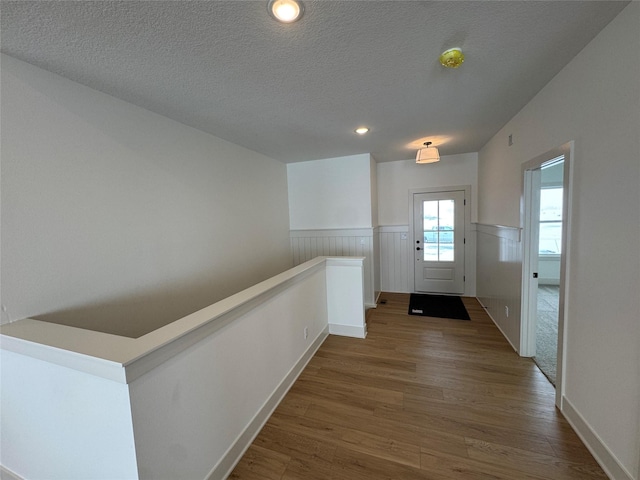 doorway featuring dark wood-style flooring, wainscoting, and a textured ceiling