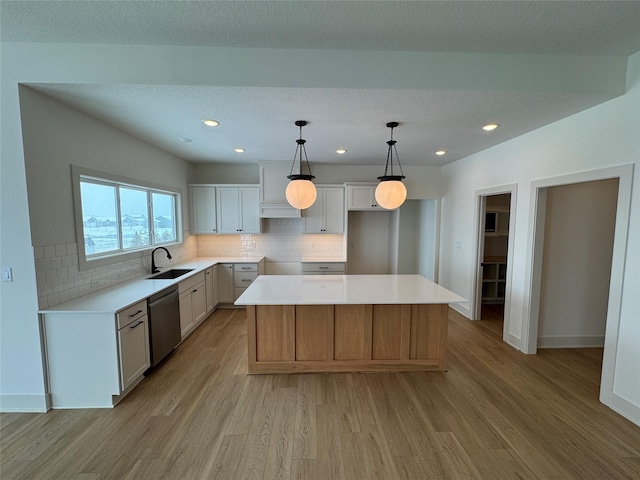 kitchen with a sink, light wood finished floors, a kitchen island, and stainless steel dishwasher