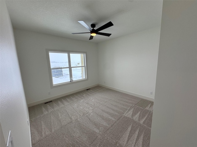 empty room with ceiling fan, a textured ceiling, light carpet, visible vents, and baseboards