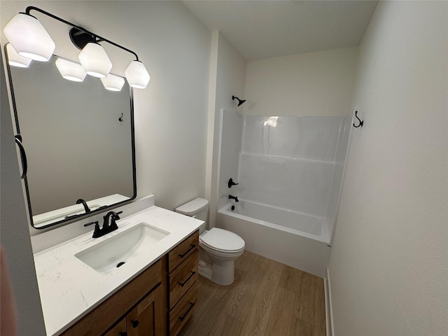 bathroom with washtub / shower combination, vanity, wood finished floors, and toilet