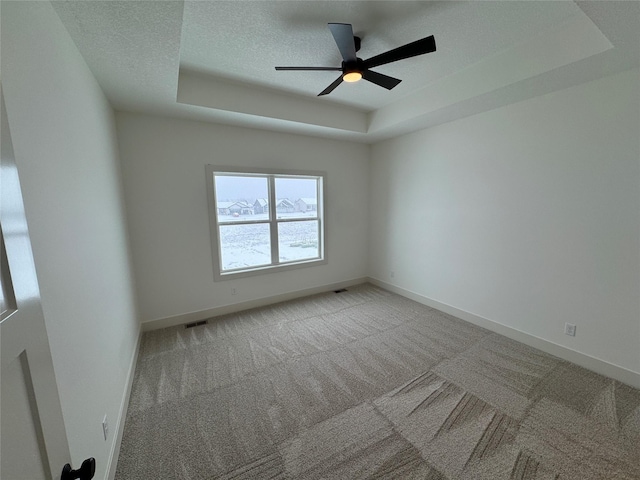 spare room with baseboards, visible vents, a raised ceiling, a textured ceiling, and carpet floors