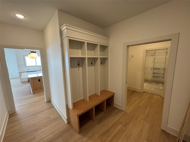 mudroom featuring baseboards, a textured ceiling, and light wood finished floors