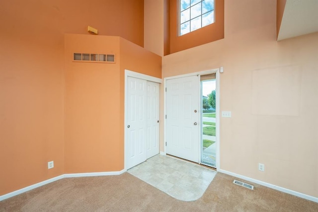 entryway featuring light colored carpet and a high ceiling