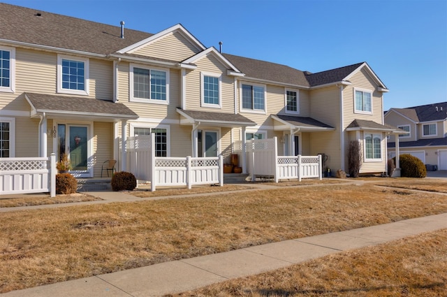 townhome / multi-family property featuring covered porch, a shingled roof, and fence