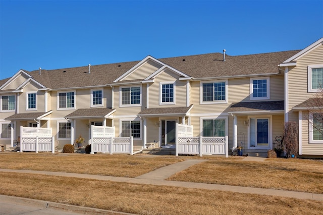 view of property featuring a shingled roof and a front yard