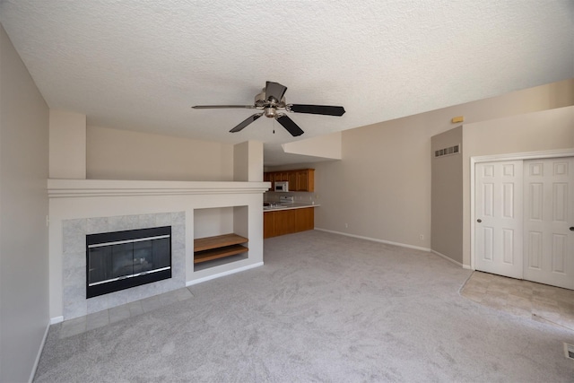 unfurnished living room featuring baseboards, visible vents, light colored carpet, and a tile fireplace