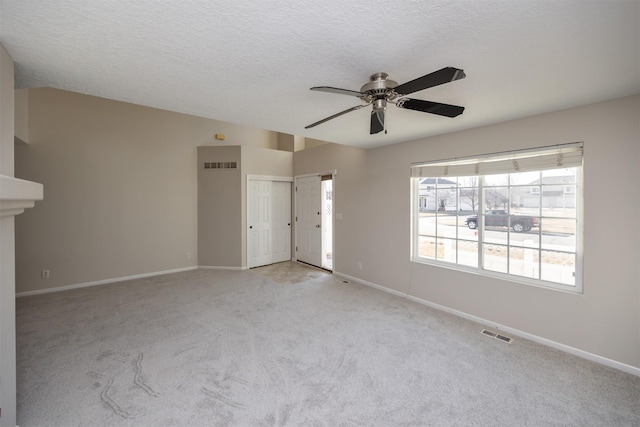 empty room featuring visible vents, light carpet, baseboards, and a textured ceiling