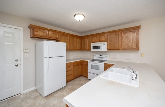 kitchen with brown cabinets, white appliances, light countertops, and a sink