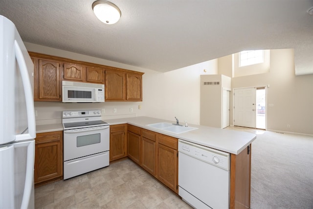 kitchen featuring brown cabinets, light countertops, a sink, white appliances, and a peninsula