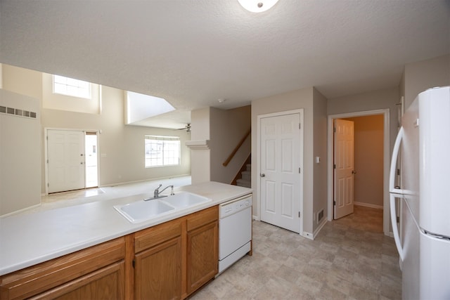 kitchen featuring white appliances, a sink, a ceiling fan, light countertops, and brown cabinets