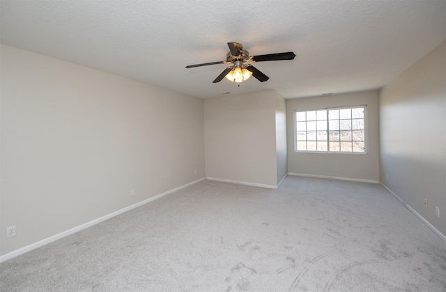 unfurnished room featuring light carpet, ceiling fan, a textured ceiling, and baseboards