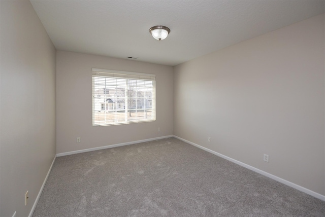 spare room featuring carpet flooring, visible vents, and baseboards