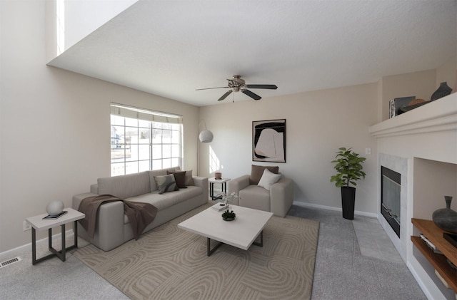 living area with ceiling fan, carpet flooring, visible vents, baseboards, and a tiled fireplace