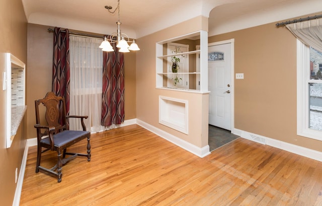 unfurnished room with hardwood / wood-style floors, an inviting chandelier, and a healthy amount of sunlight