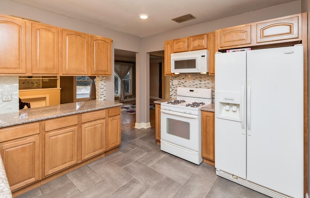 kitchen with kitchen peninsula, tasteful backsplash, light stone counters, white appliances, and light brown cabinets