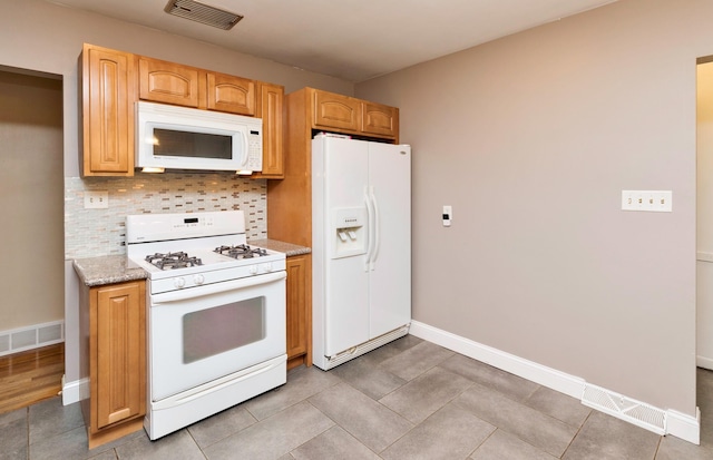 kitchen featuring light tile patterned flooring, light stone countertops, white appliances, and tasteful backsplash