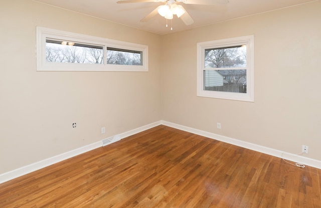 empty room with hardwood / wood-style floors, plenty of natural light, and ceiling fan