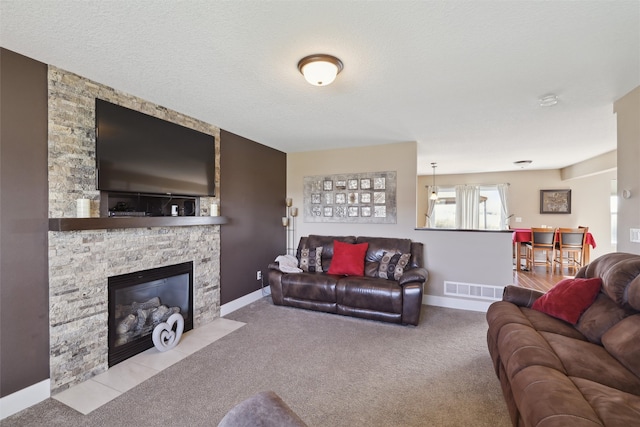 carpeted living room featuring a textured ceiling and a stone fireplace