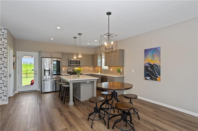 kitchen with a kitchen bar, backsplash, stainless steel appliances, gray cabinets, and a kitchen island